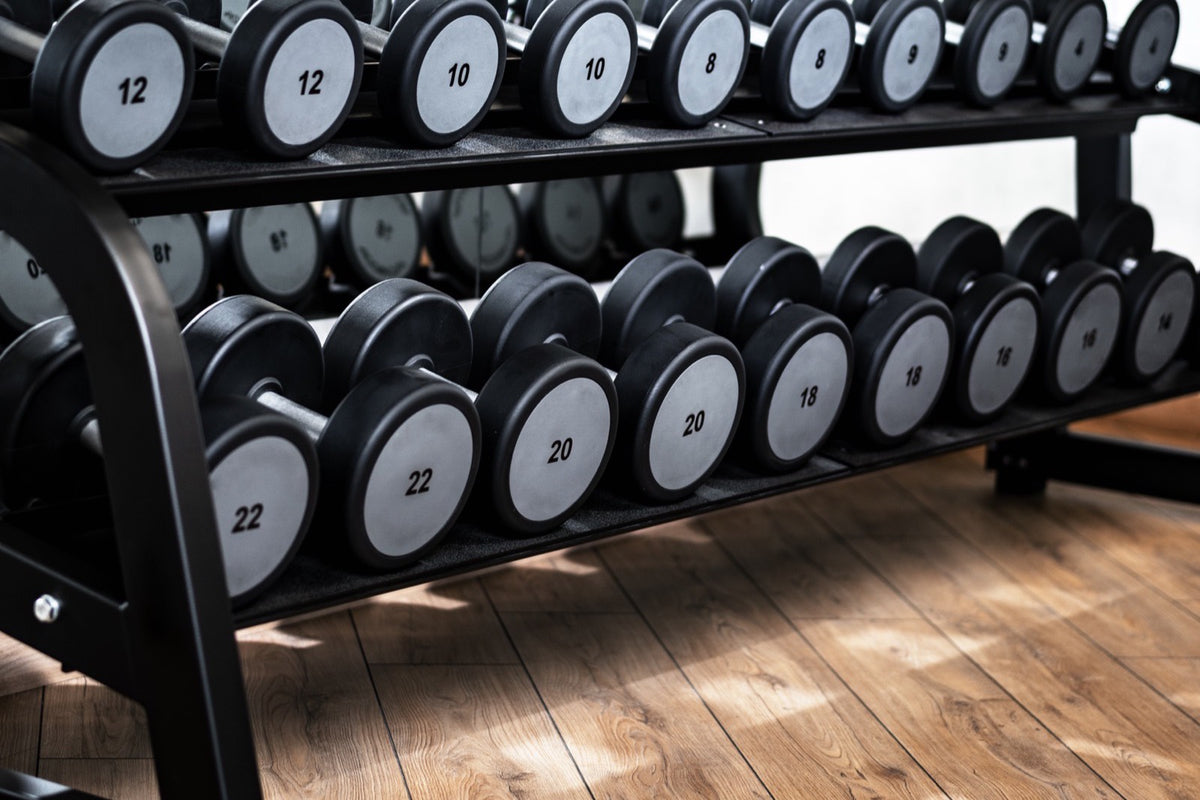 Rack de mancuernas ordenadas en un gimnasio, sobre piso de madera