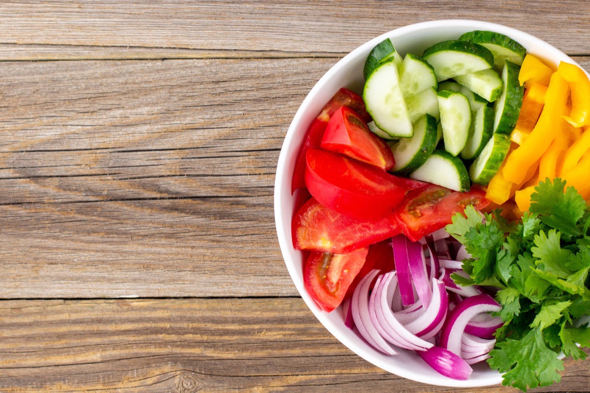 Bol de ensalada con verduras frescas sobre una mesa de madera rústica