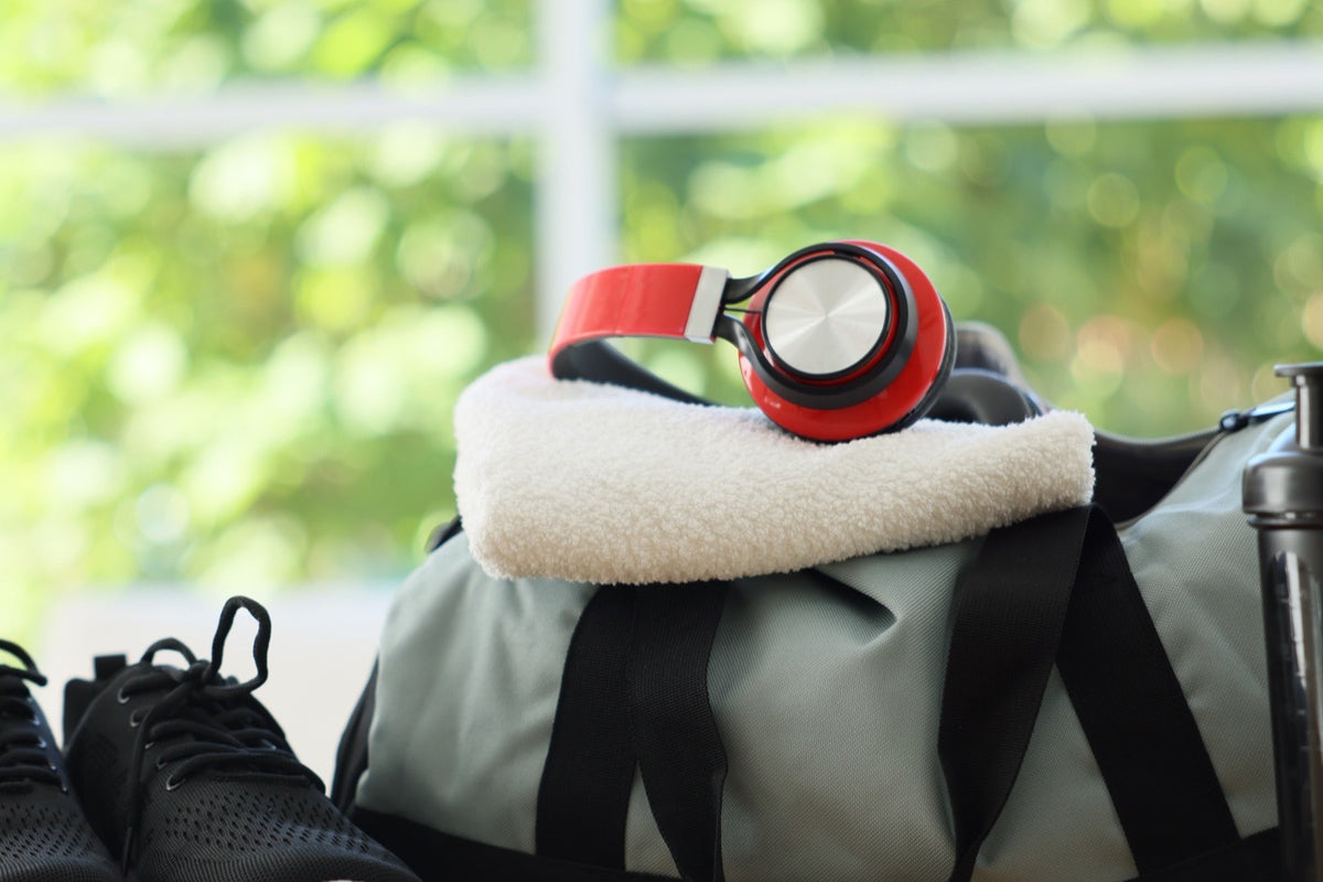 Bolso de gimnasio con zapatillas y botella junto a una ventana con luz